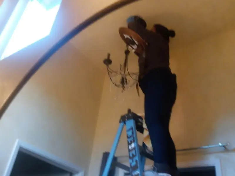 Electrician installing a chandelier in a Edna residence
